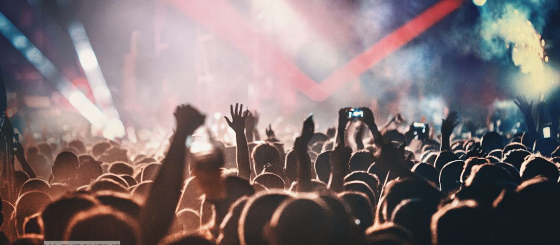 Luxury limousine for friends enjoying a concert night out, vibrant stage lights in the background and a professional chauffeur providing comfortable, VIP transportation.